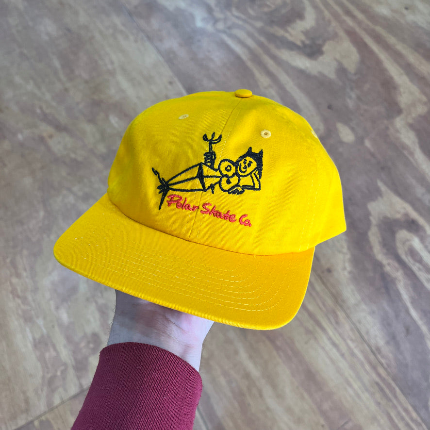 yellow hat with a black and red graphic of a devil woman