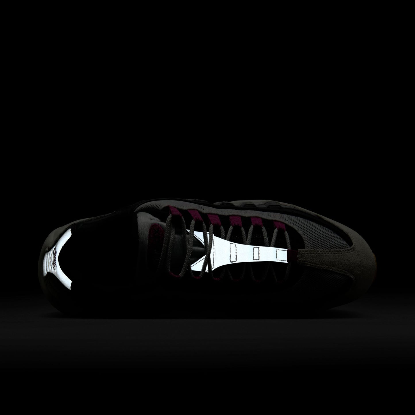 sneaker with reflective sole details visible on a black background
