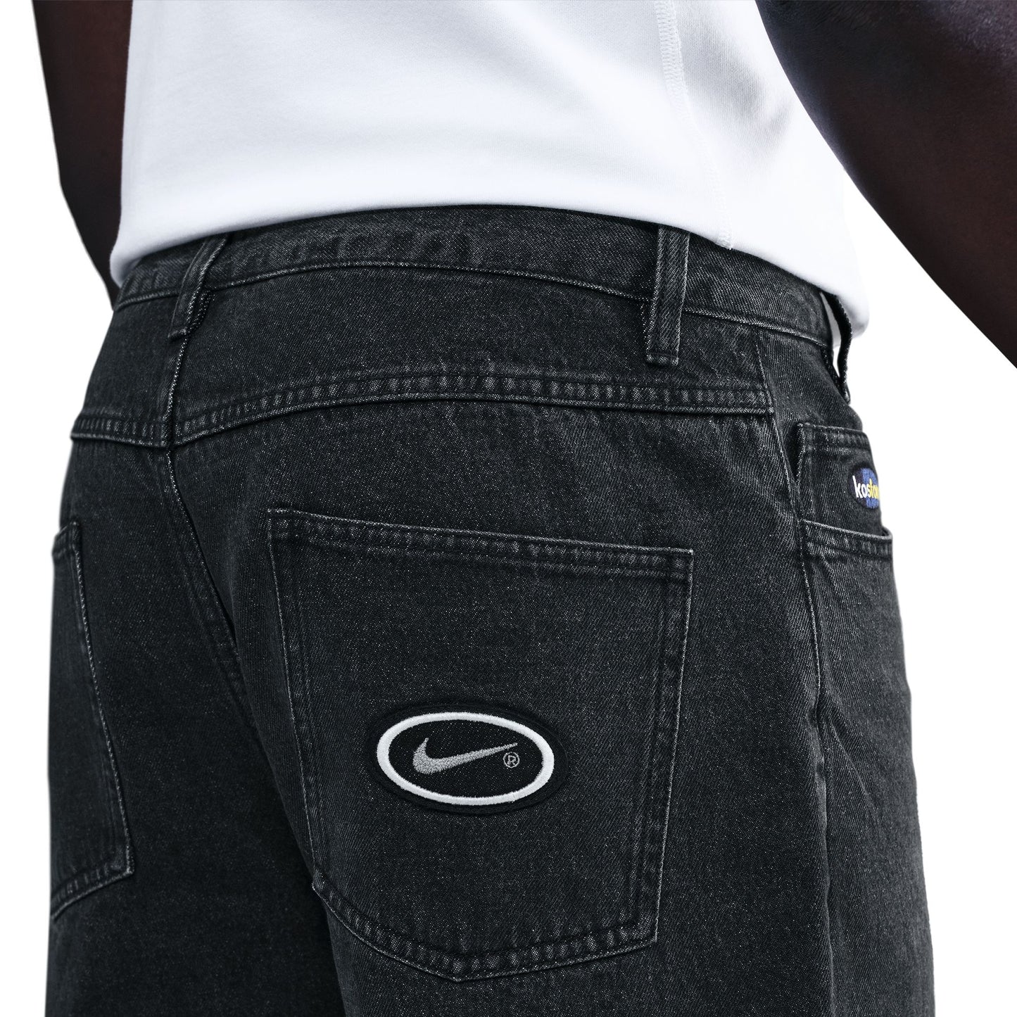 Black jeans with a Nike logo on the back pocket against a white background