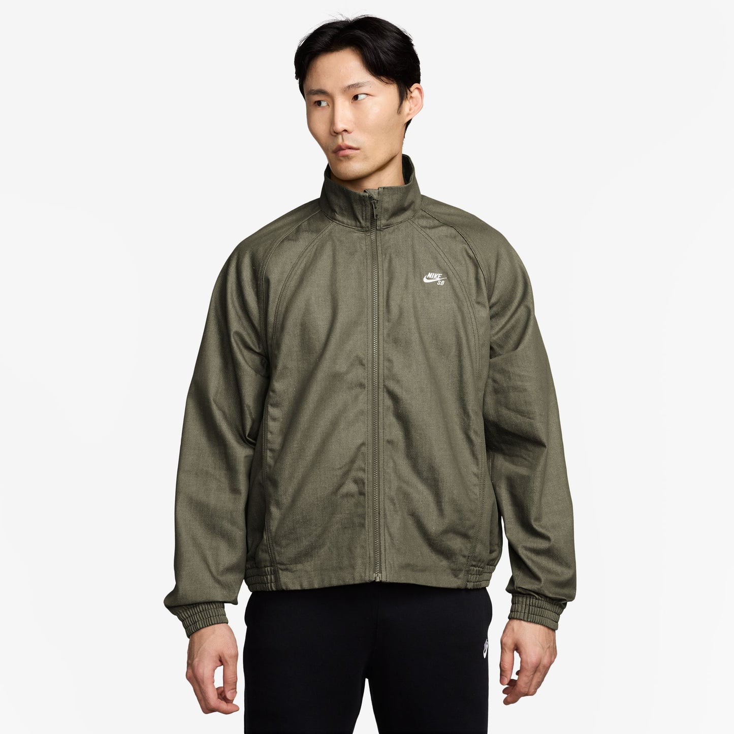Person wearing a green jacket with a brand logo on a white background