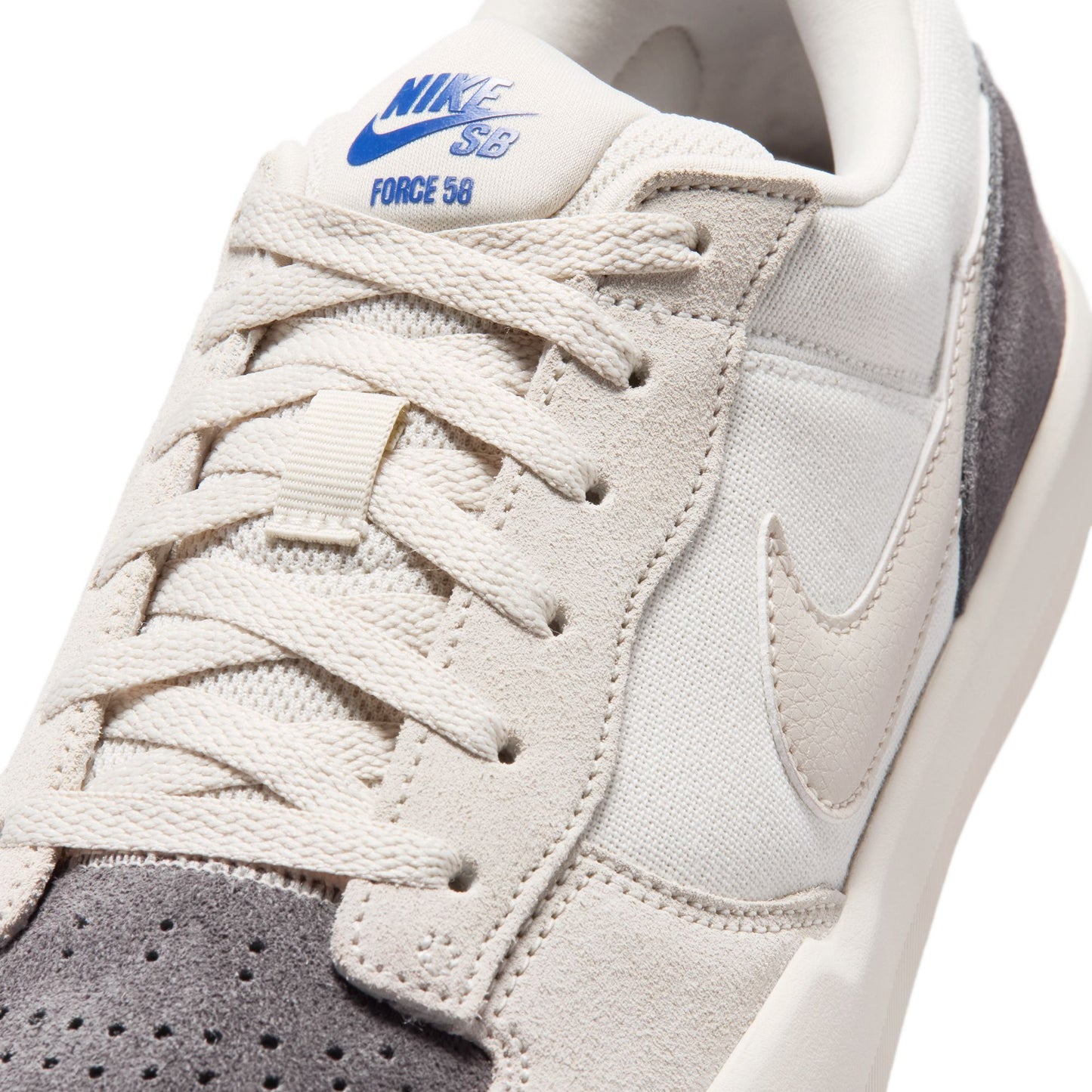 Close-up of a beige sneaker with white laces and a visible Nike logo on a white background