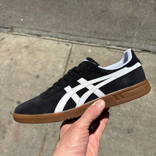 Side view of black suede skateboard sneaker with white accents and gum sole