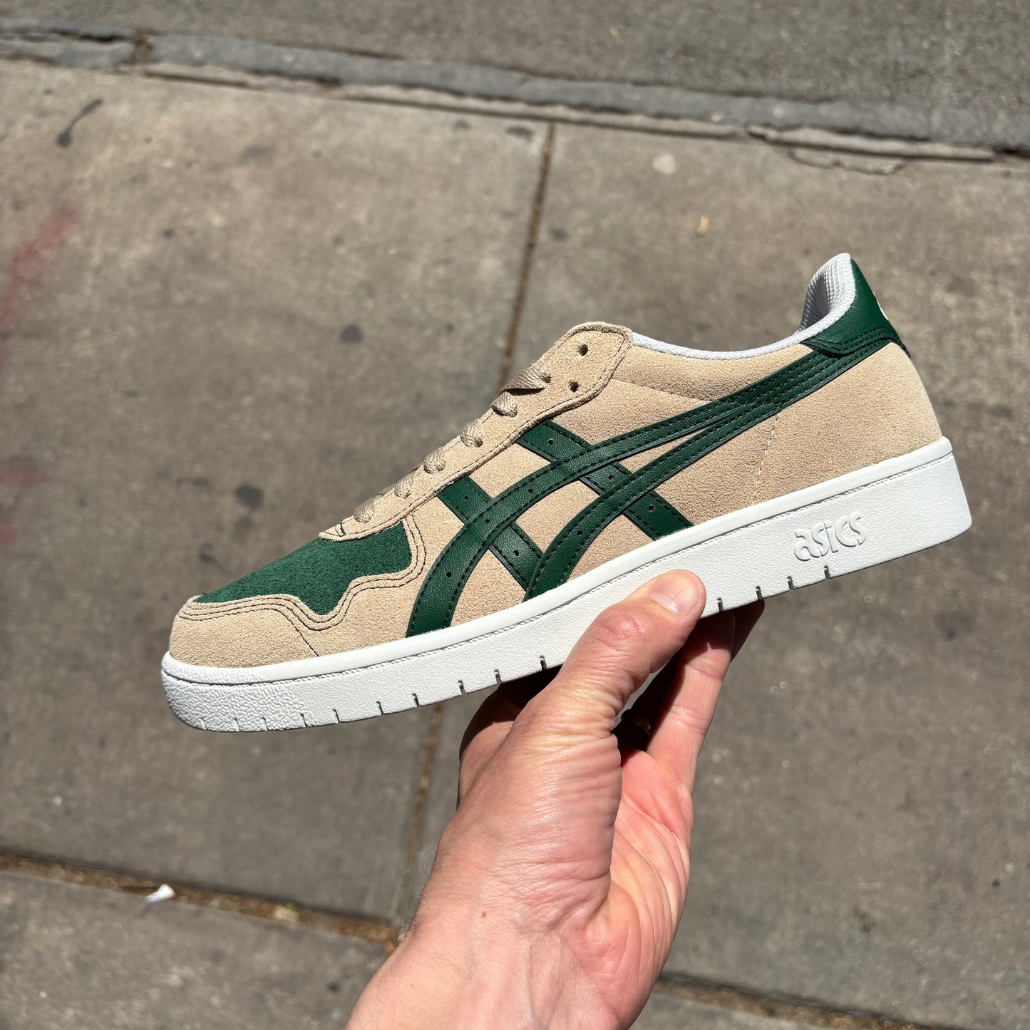 side view of cream colored suede skateboard shoe with green accents and white sole