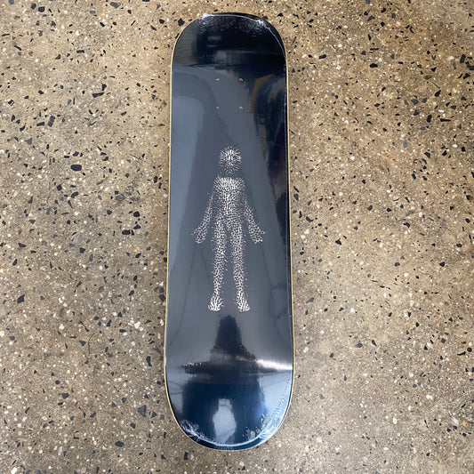 black skateboard deck with silver figure covered in spikey pins in the center