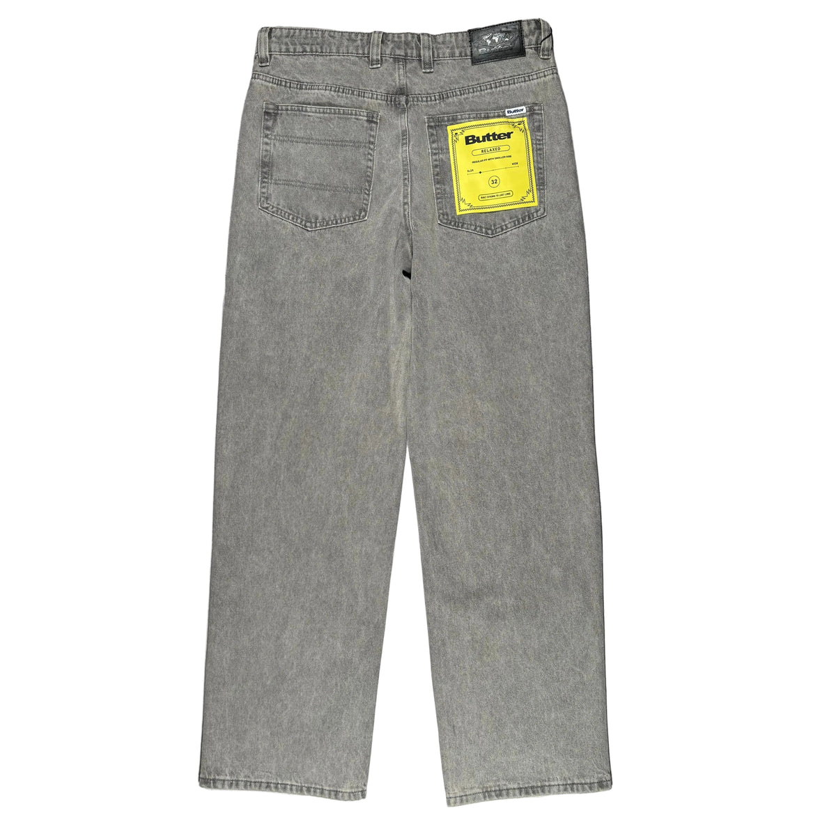 Gray denim jeans laid flat on a white surface, viewed from the back. The jeans have a yellow Butter brand tag in the back pocket.