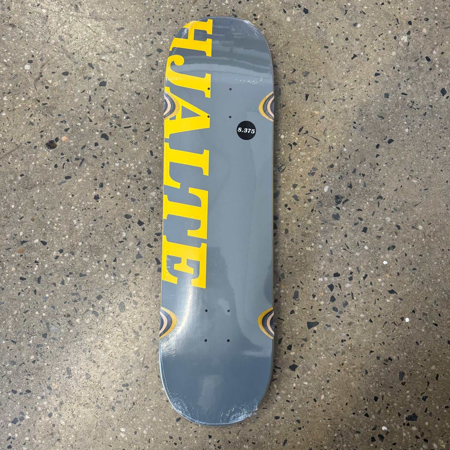 grey skateboard deck with bright yellow text