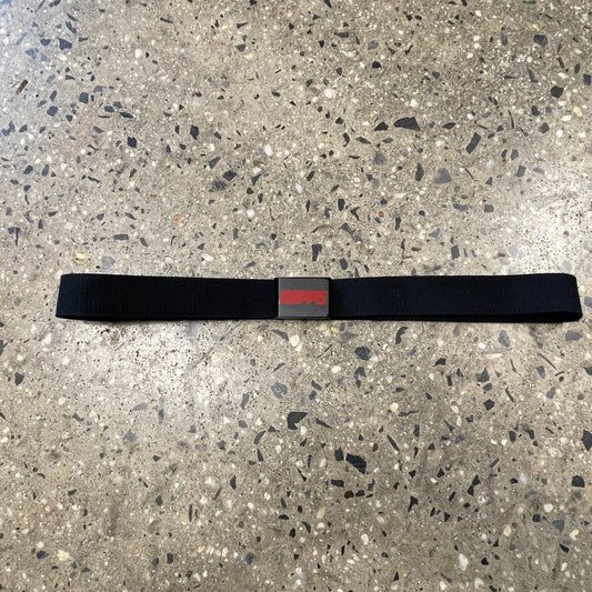 elongated view  of black webbed belt with red hopps logo on black belt buckle