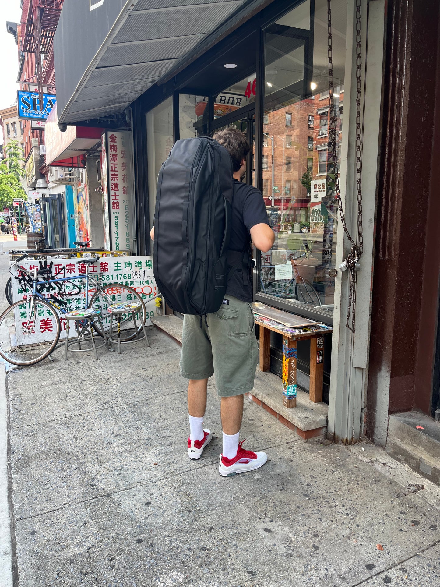 man wearing DB skate travel bag on back in front of skatebaord shop