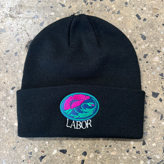 Pink and green flower logo with LABOR underneath, on black folded beanie