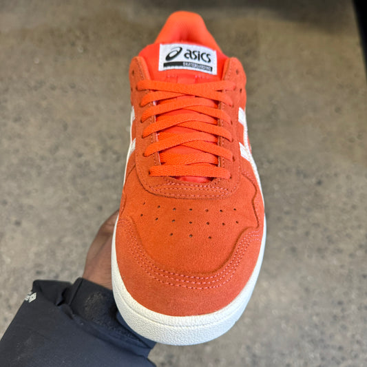 orange suede sneaker with white stripes and sole, front view