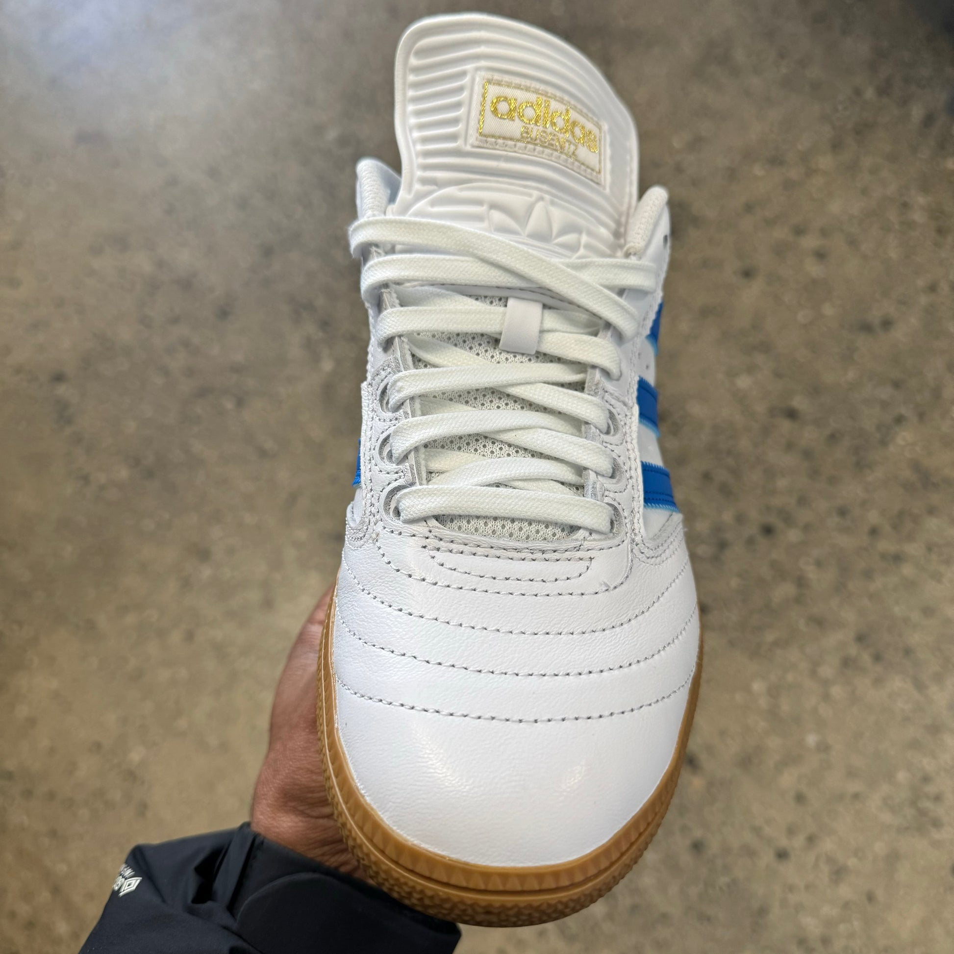 front view of white leather sneaker with gold logo
