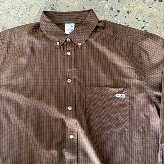 closeup of brown button down shirt, white buttons, pocket on chest