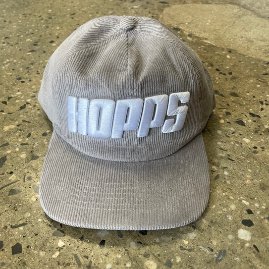 front view of large white hopps logo on grey corduroy hat