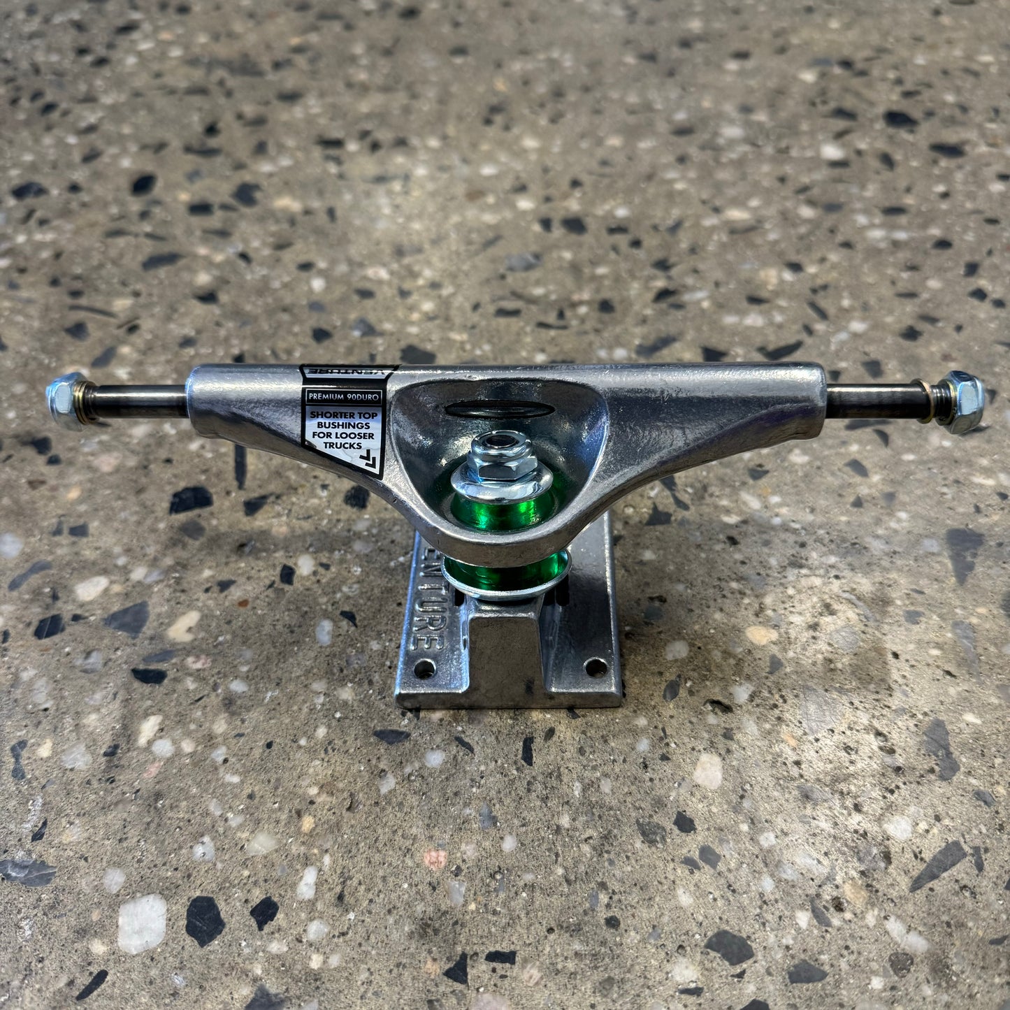 rear view of silver polished skateboard trucks, green bushings visible