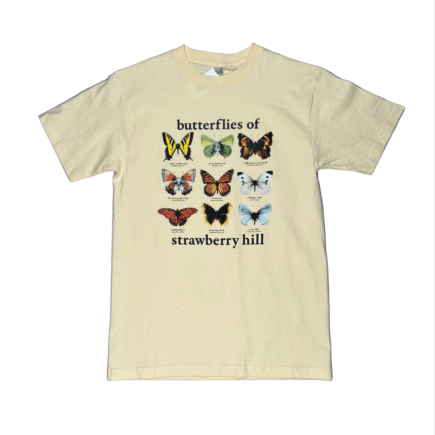 cream colored t-shirt with butterfly illustrations and text on a gray surface