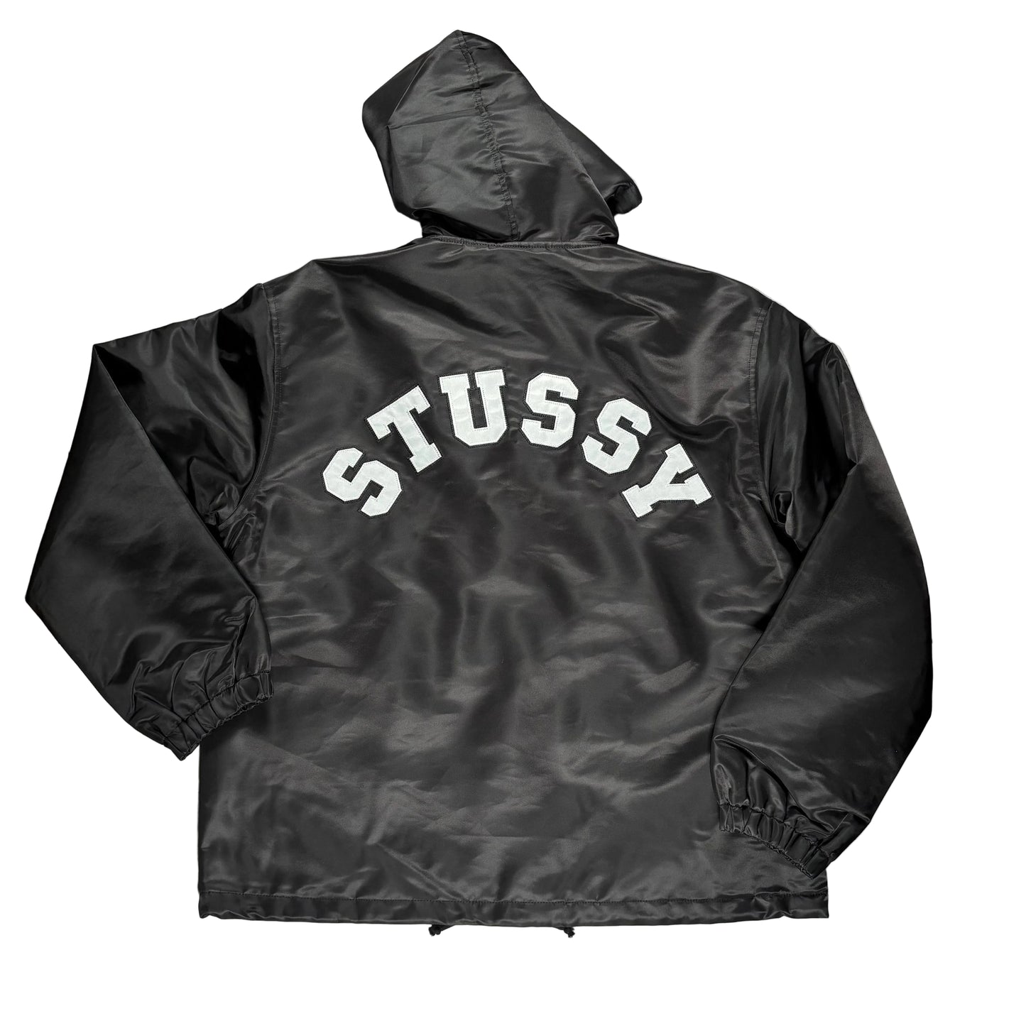Black jacket with 'Stussy' branding on a white surface