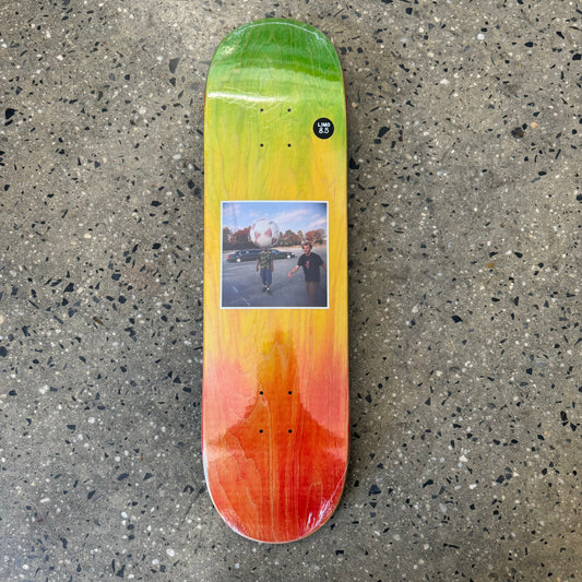 green, yellow and red woodstained skateboard deck with photograph in the center