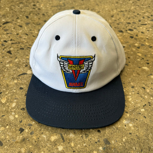 white hat with navy blue brim with blue red and yellow embroidery in the center