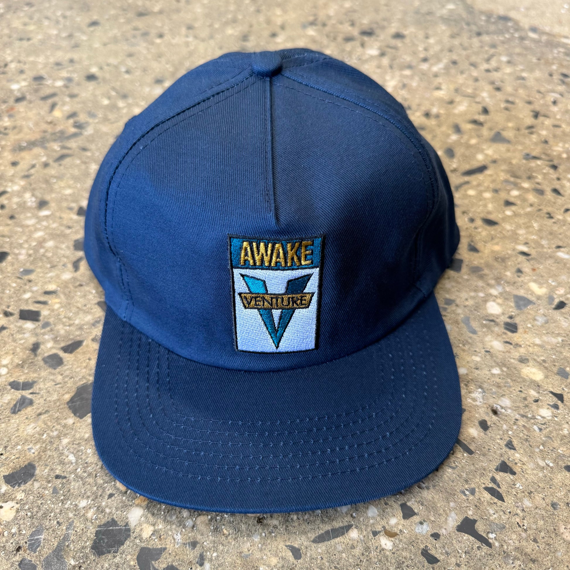 navy hat with venture logo in teal/yellow text in the center of the hat