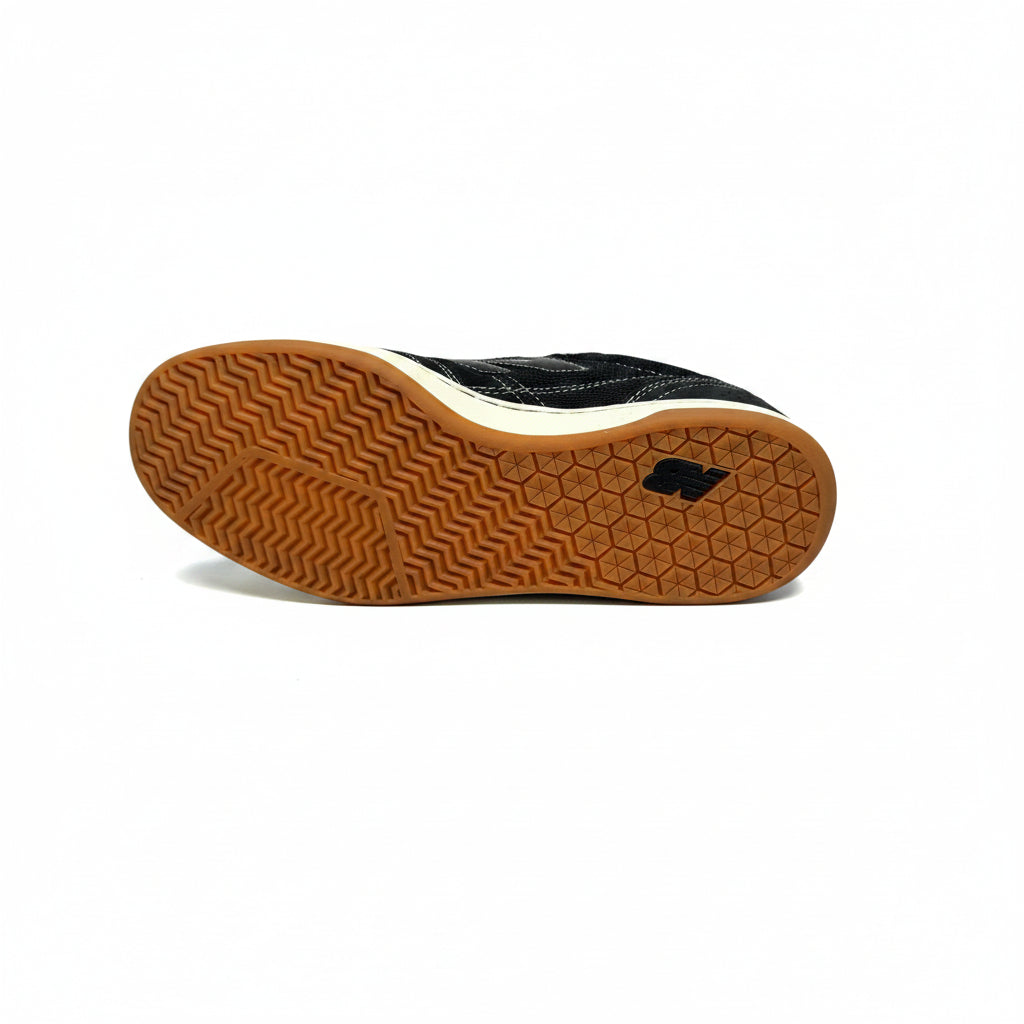 Black sneaker with brown sole on a white surface