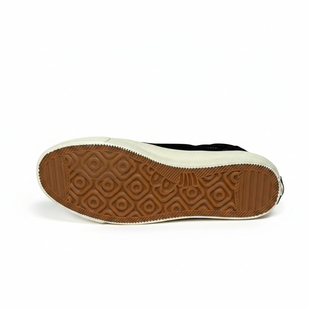 Sole of a black shoe with brown tread pattern on a gray background