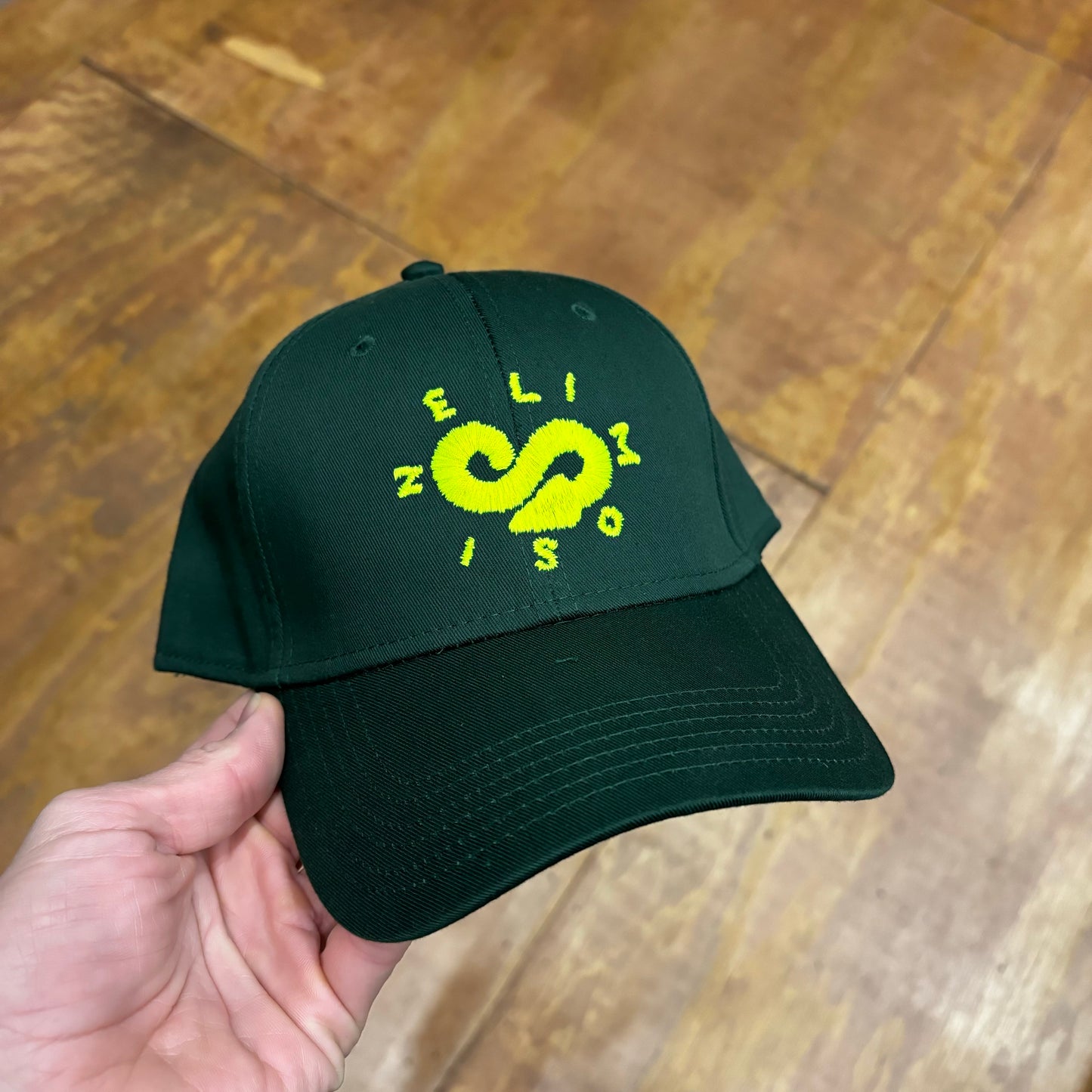 front view of yellow embroidered infinity logo on green hat