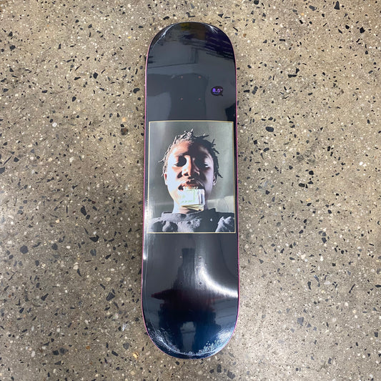 photo of boy with money in mouth on black skate deck