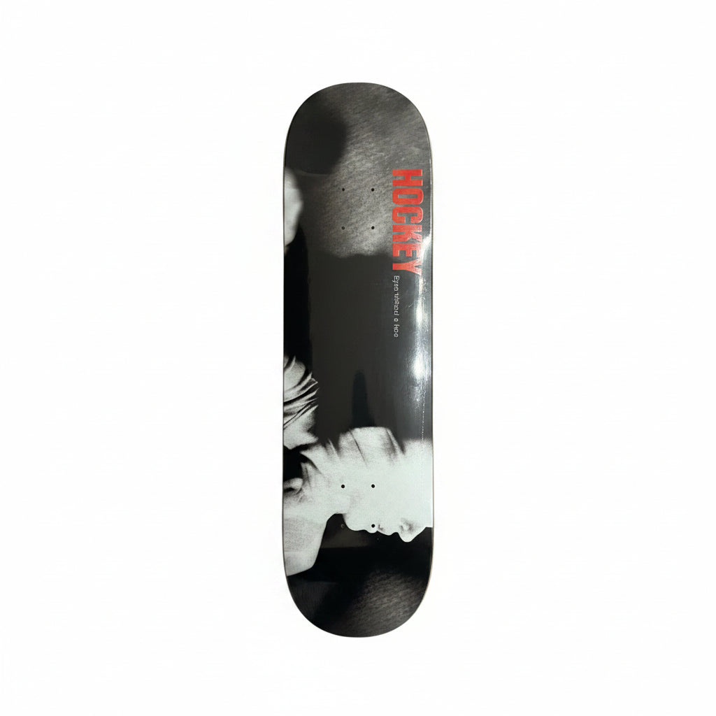 Skateboard deck with a black and white design and red text on a white surface.