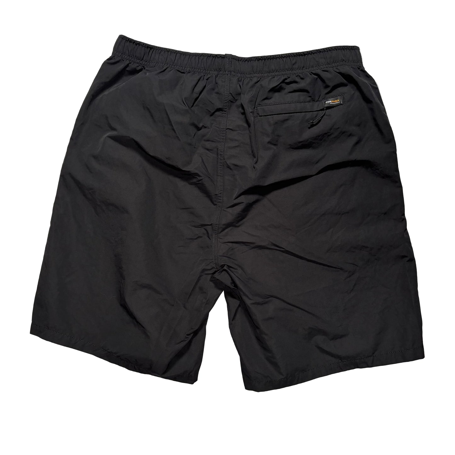 view of rear of Black elastic waist stussy shorts on a gray concrete surface