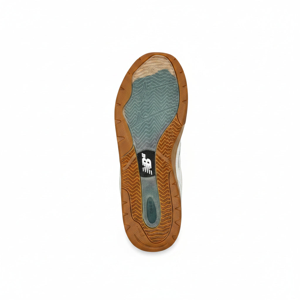 A single sneaker shown from the sole view, featuring a brown gum outsole, a teal and beige textured midsole, and a black New Balance logo patch, set against a white background.