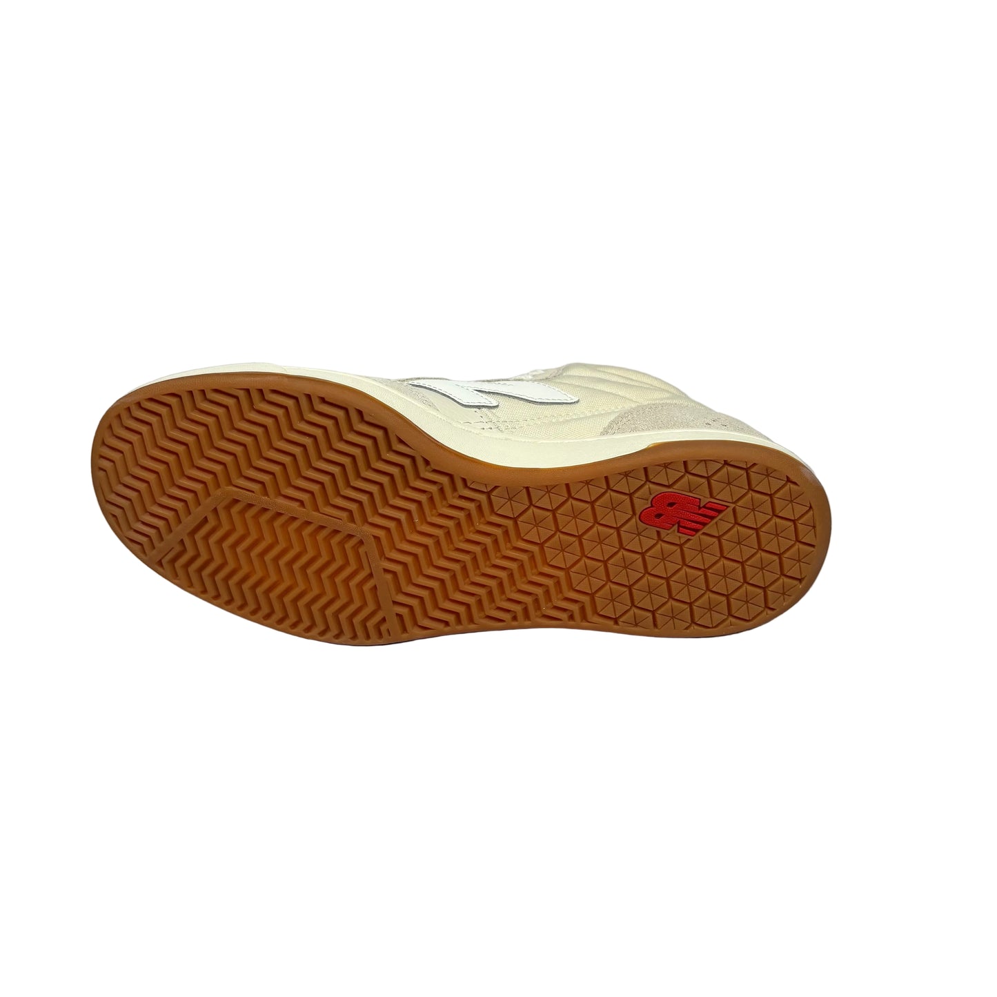 The outsole of a New Balance sneaker, showing a cream-colored upper, a brown wavy treaded rubber sole, and a small red New Balance logo on the heel, set against a white background.