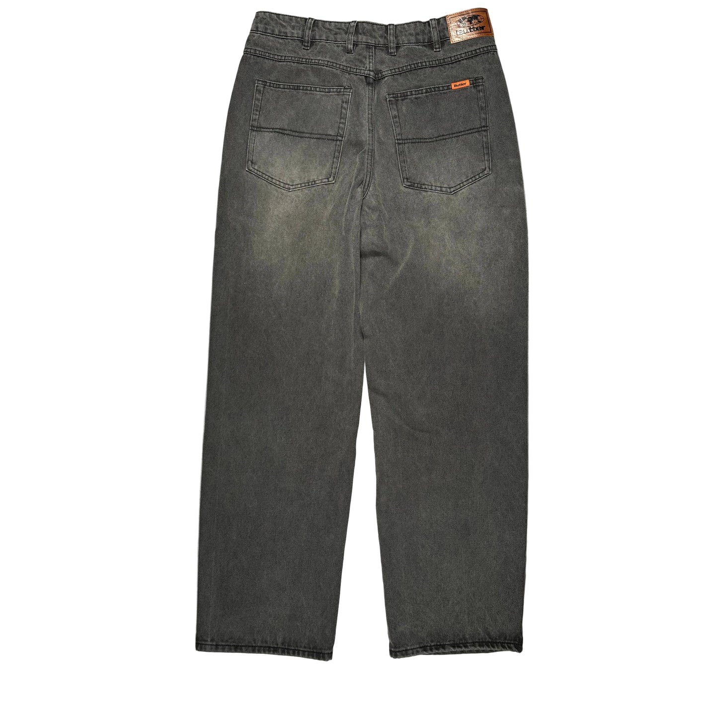 Back view of a pair of faded black denim jeans laid flat on a white surface. The jeans have two pockets with a brown patch on the waist band.