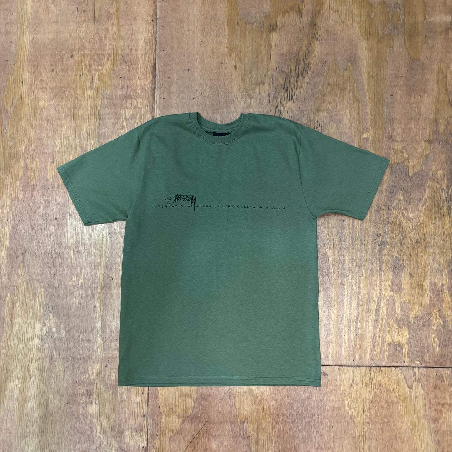 olive green t-shirt with STUSSY INTERNATIONAL printed across the front