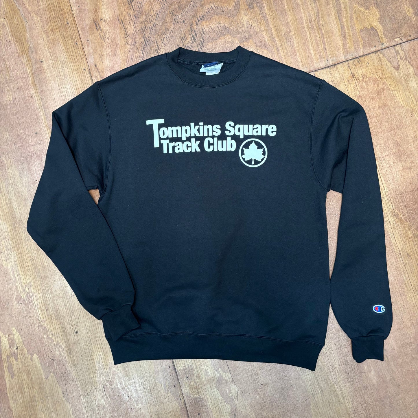 front view of navy crewneck sweatshirt with TOMPKINS SQUARE TRACK CLUB across chest
