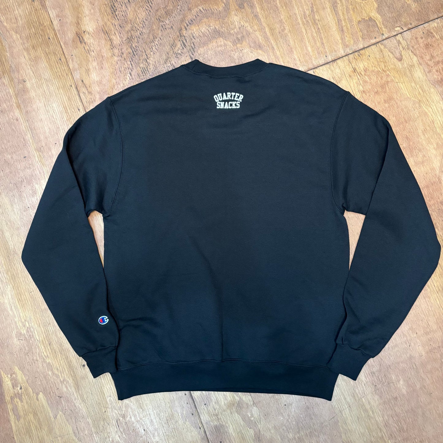 view of back of crewneck sweatshirt with QUARTER SNACKS on top center of sweatshirt