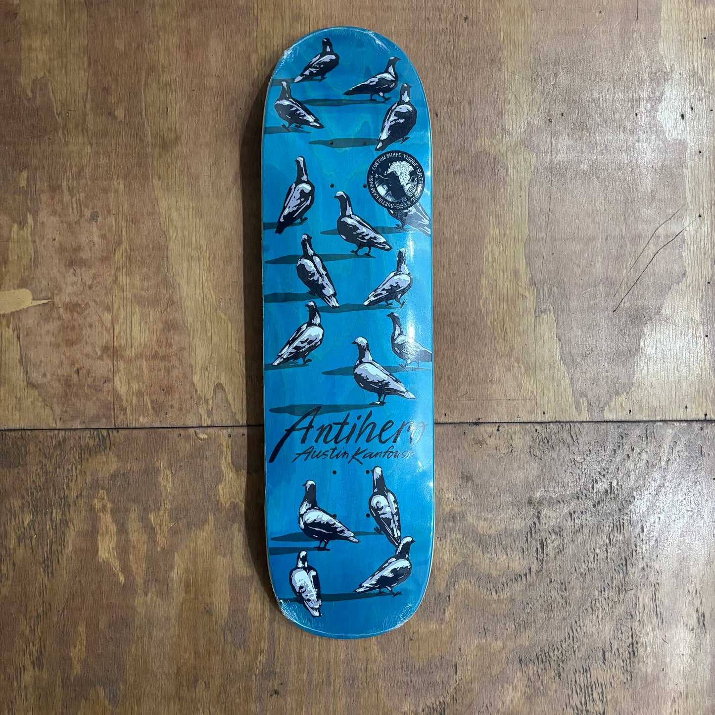 Shaped skateboard deck with pigeons prined on woodgrain deck