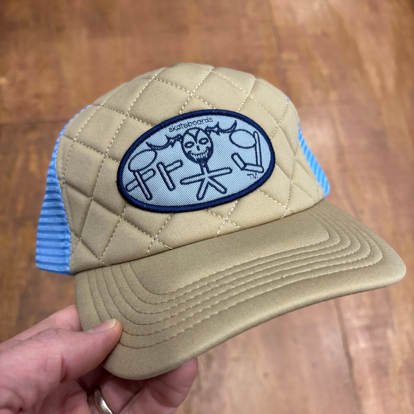 straight on view of tan and light blue trucker hat with oval FROG SKATEBOARDS patch on it