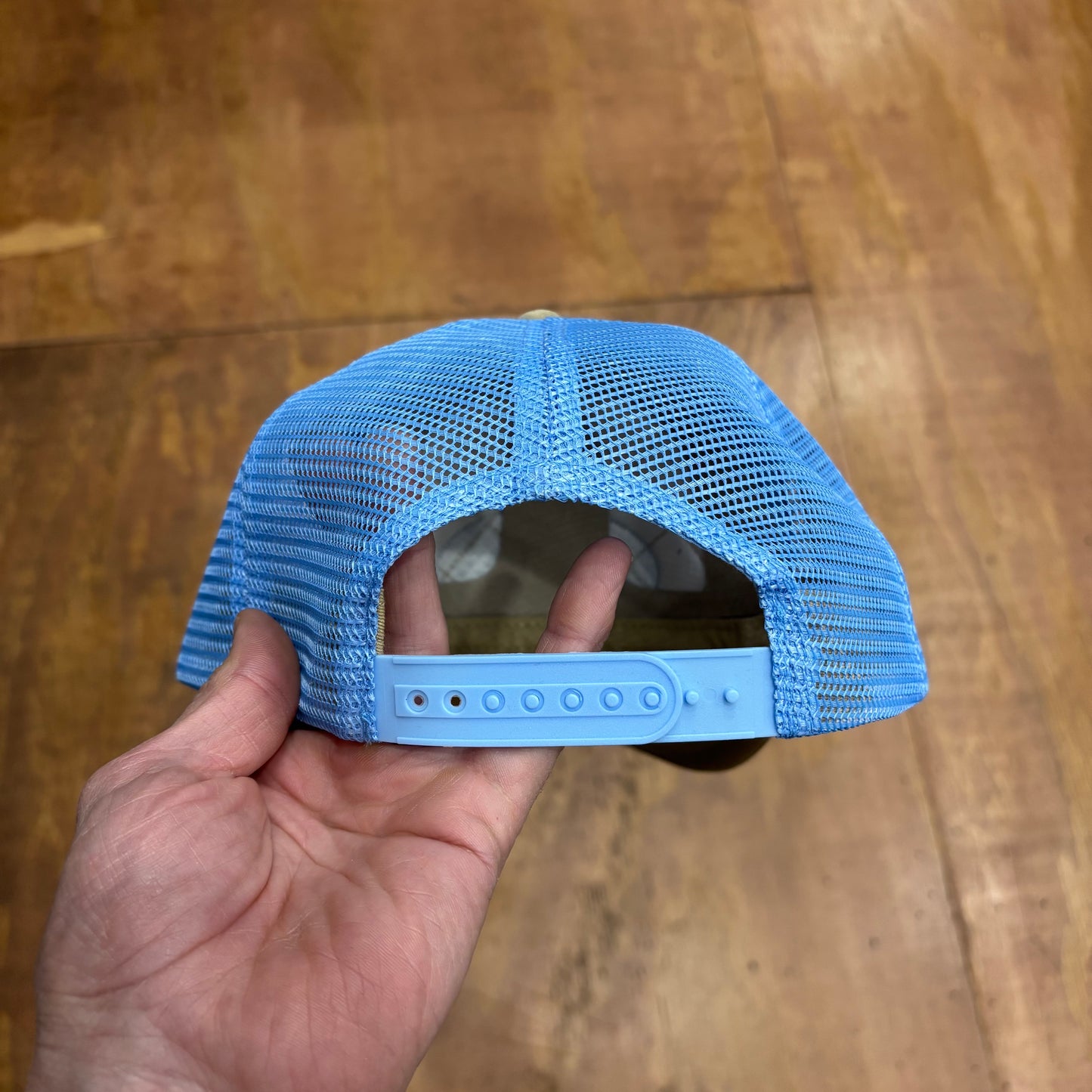 view of the rear of trucker hat with light blue mesh, and snap closure
