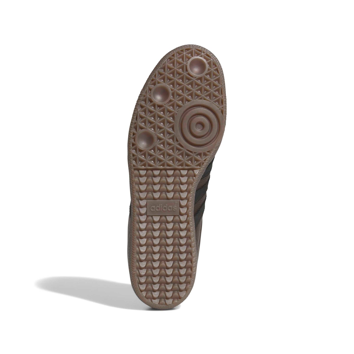 The textured brown rubber outsole of an Adidas shoe, showing the circular and geometric tread patterns, photographed on a white background with a soft shadow.