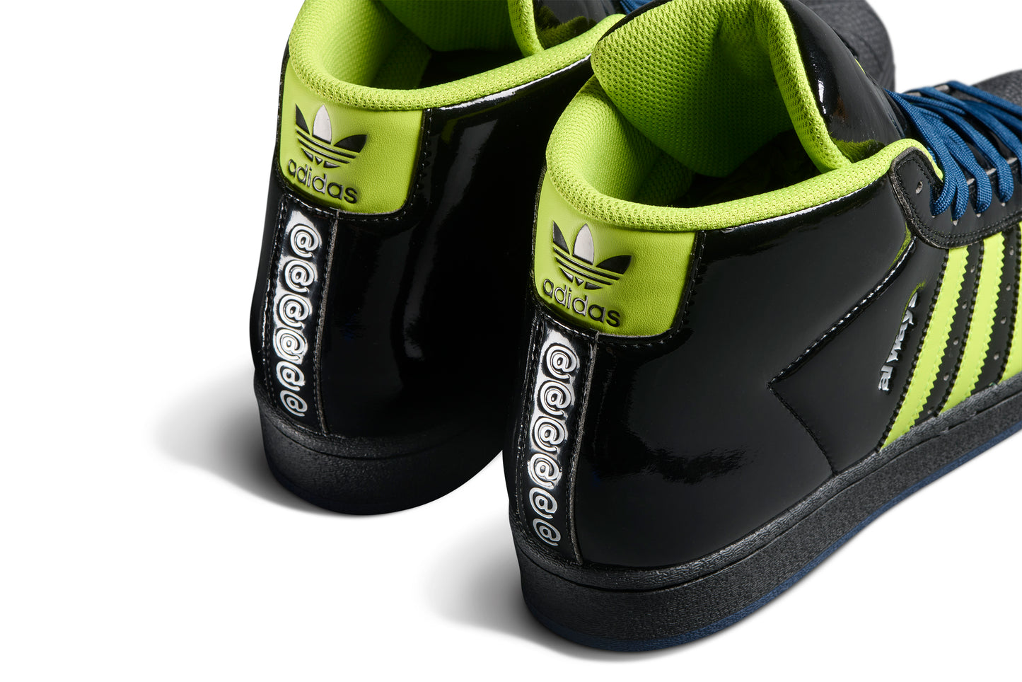 rear view of black patent leather mid top sneaker with the 'at sign' vertically embossed on heel of shoe