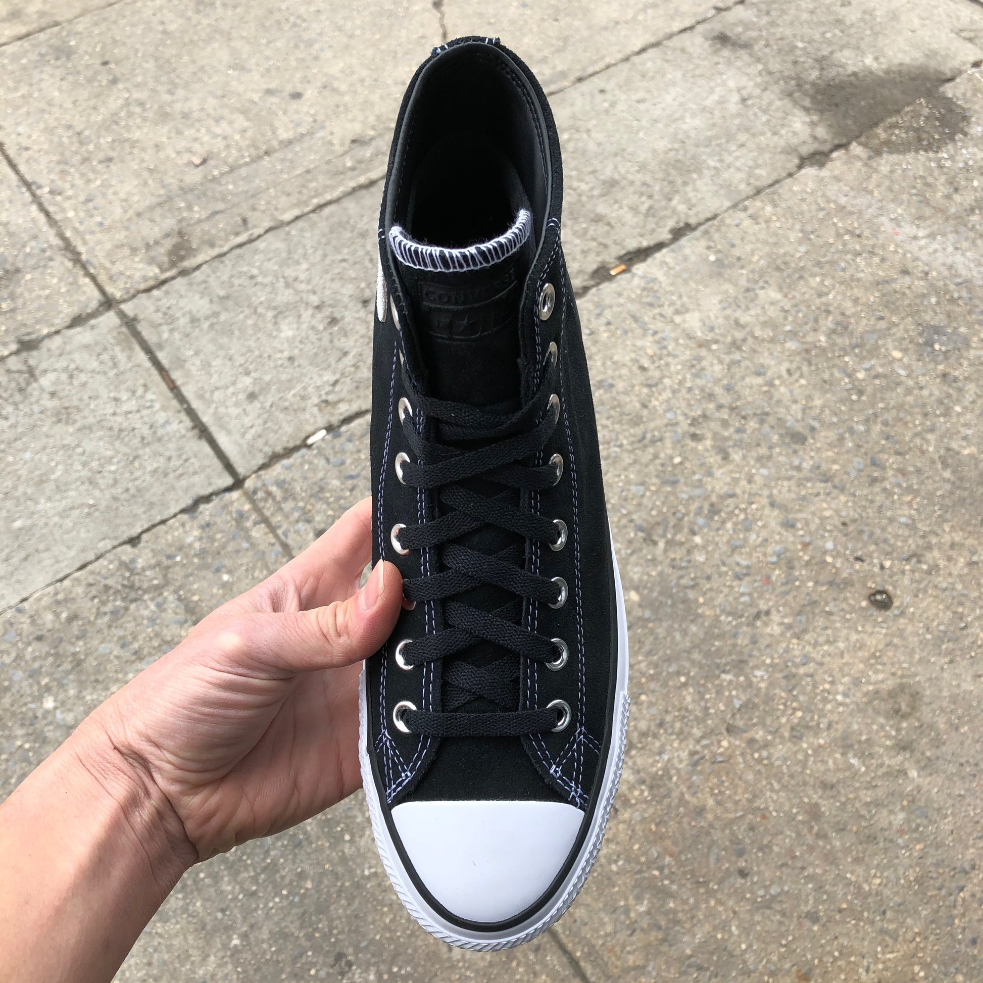 black hi top sneaker with white sole and toe, top view