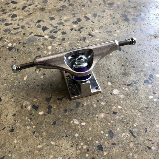 rear view of silver polished venture skateboard truck, purple bushings are visible