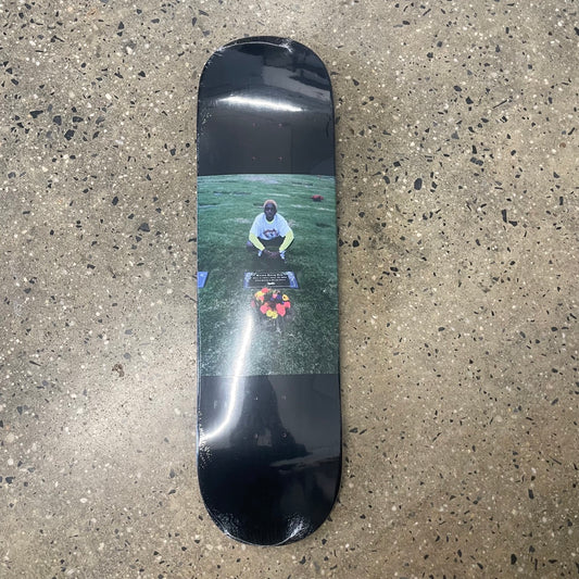 person sitting at grave site on black skate deck