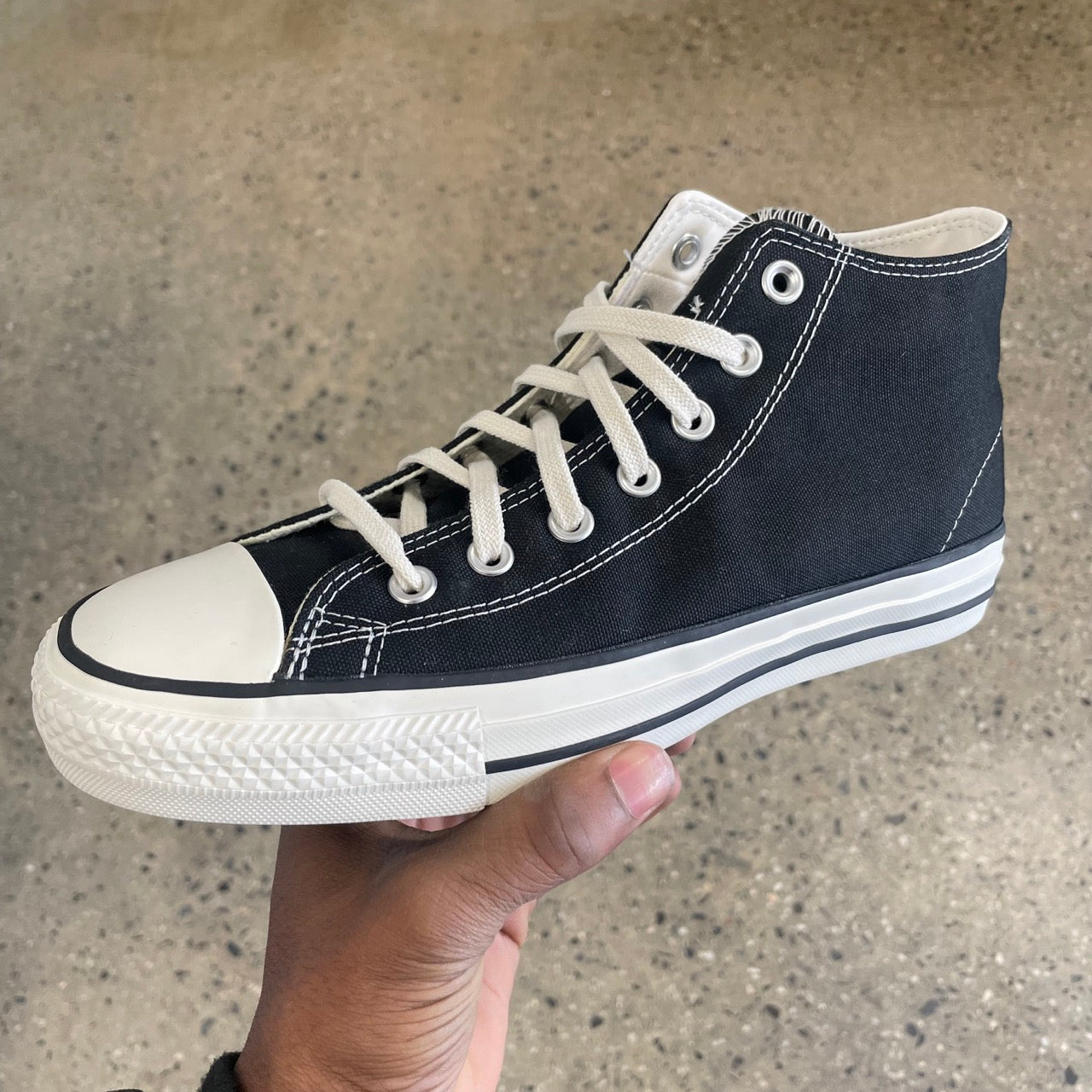 black canvas sneaker with white sole, toe, and stitch, side view