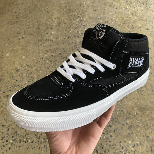 Side view of black suede and canvas skateboard shoe with white contrast stitching, white outsole