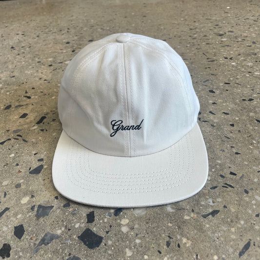 Front view of black grand script logo embroidered on white six panel cap