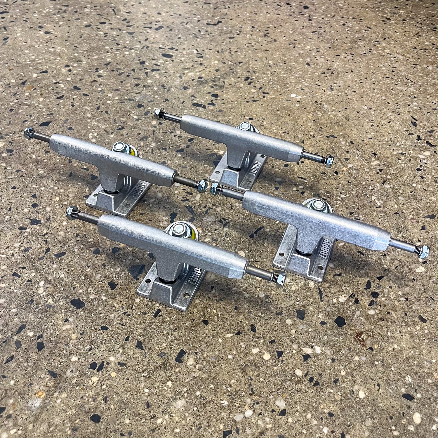 four silver skateboard trucks on the floor