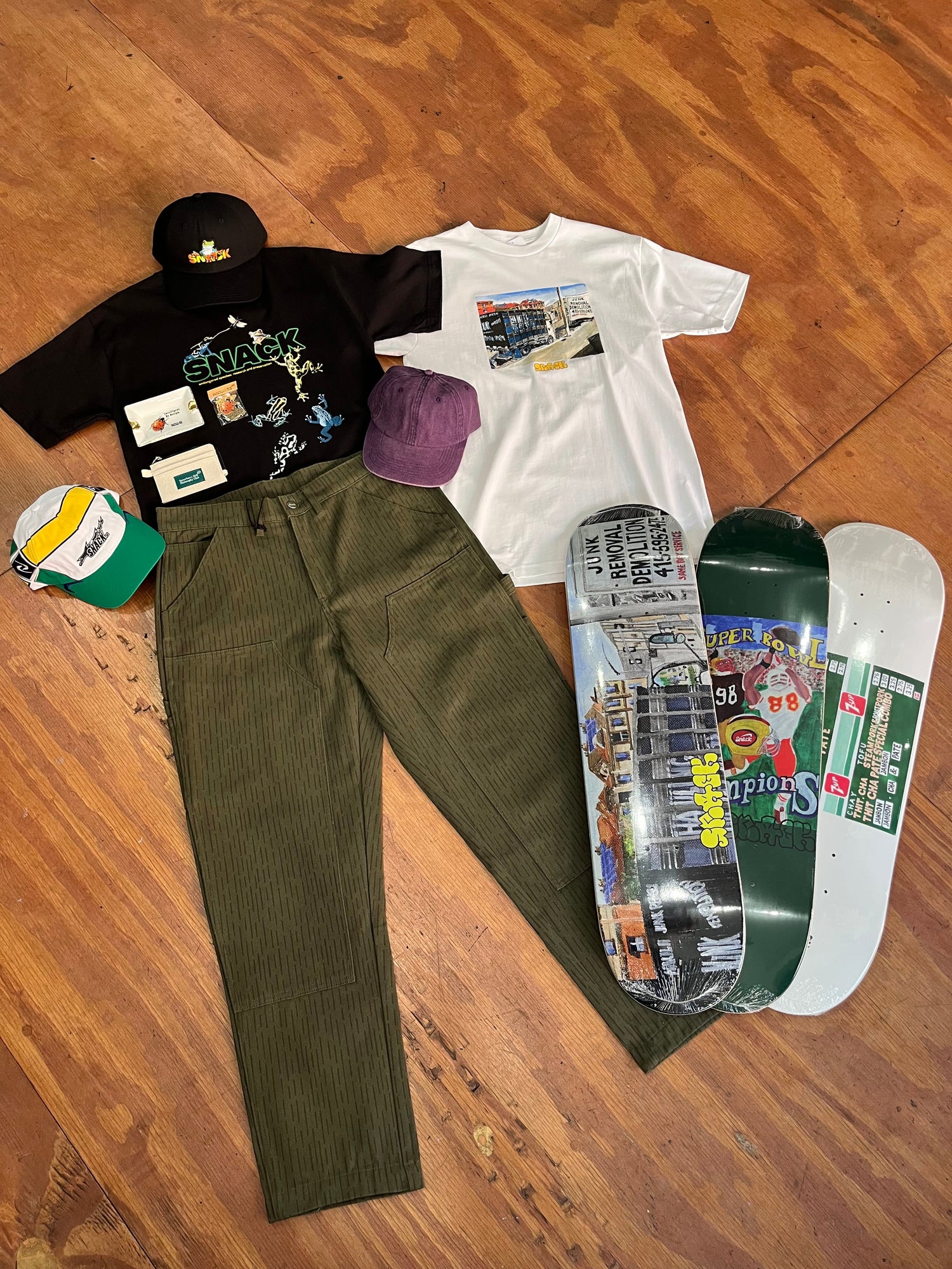 skateboard decks, hats, and clothing on a wood floor
