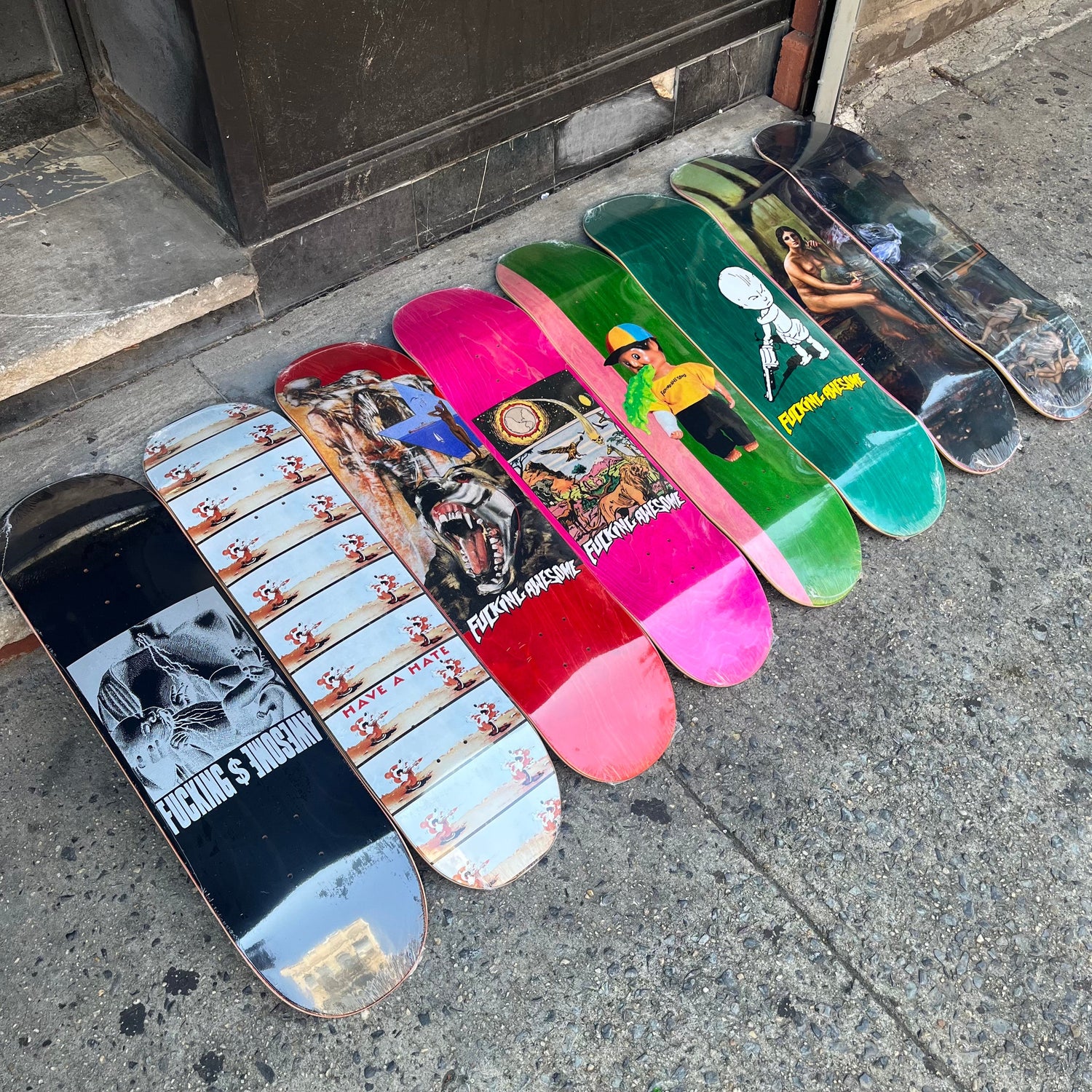 bright colored hand style and graphic design based skateboard graphics against a sidewalk