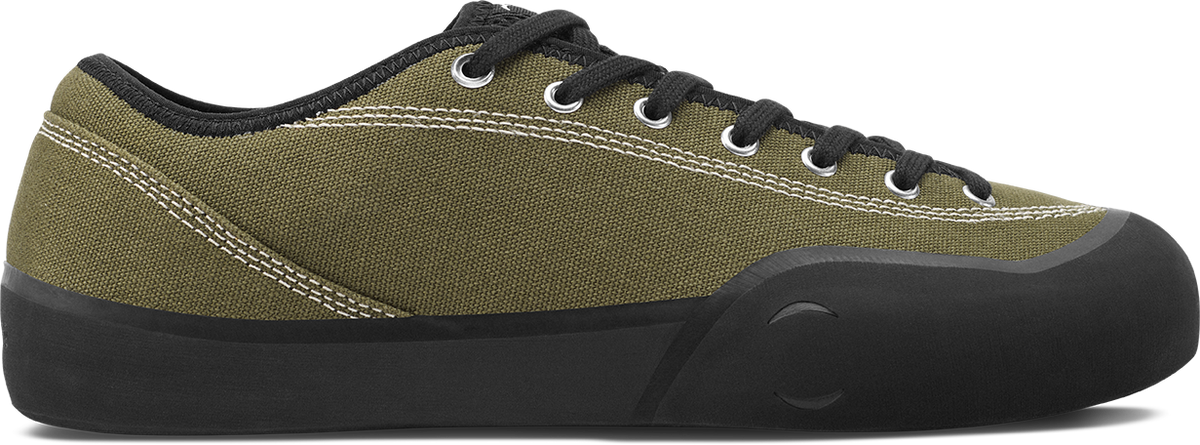 An olive green canvas low-top sneaker with black laces, a black collar, and a black rubber sole, shown from a side profile on a white background.